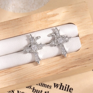 Silver cross stud earrings with sparkling crystals displayed on a wooden jewelry stand