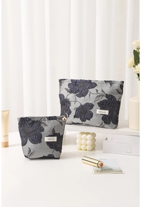 Macro detail of blue jacquard toiletry bags with floral texture and H&R logo label