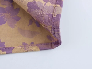 Detailed macro shot showing purple floral jacquard fabric with gold woven patterns and stitching