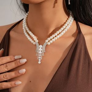 Detail of elegant double-layer faux pearl necklace with rhinestone fringe pendant on model