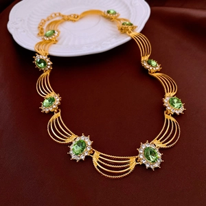 Macro detail of vintage gold necklace with multi-strand chains and green crystal pendants