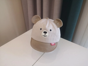 Close-up of baby sun hat with cute bear ears and striped pattern on white surface