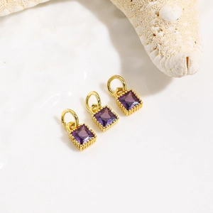 Macro shot of three purple zircon square charms with gold plating for jewelry making