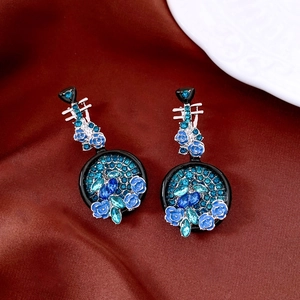 Detail of vintage musical instrument earrings with blue rhinestones on silk