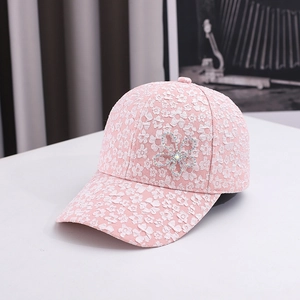 Detail view of pink lace baseball cap with floral embroidery and rhinestone flower