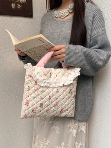 Detail of quilted floral laptop bag with soft pink handle and white lace trim detail