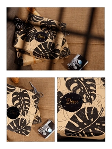 Macro detail of kraft gift wrap with black palm leaves and gold Dear sealing sticker