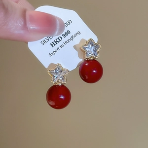 Macro detail of star earrings with red pearls and sparkling cubic zirconia stones