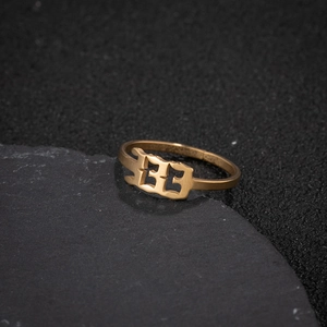 Detailed close-up of a golden gothic number 33 ring on a dark textured rock surface