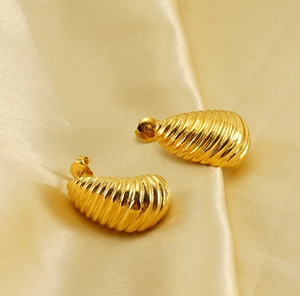 Macro detail of gold-plated croissant hoop earrings with elegant spiral texture