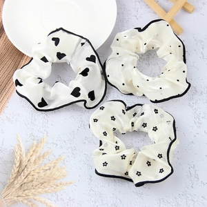 Detailed view of white mesh scrunchies set with black polka dots and heart patterns