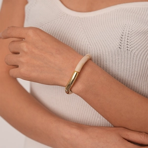 Détail d'un bracelet minimaliste en métal doré et résine beige avec design en bambou