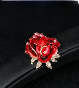 Macro detail of red enamel rose brooch with center crystal on dark display stand