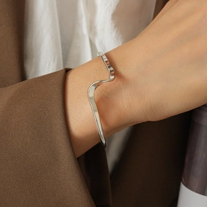 Close-up of polished S925 silver wavy cuff bracelet on wrist for a minimalist modern look