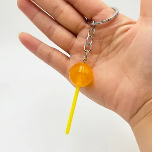 Macro shot of orange translucent lollipop keychain with gold glitter and metal hook