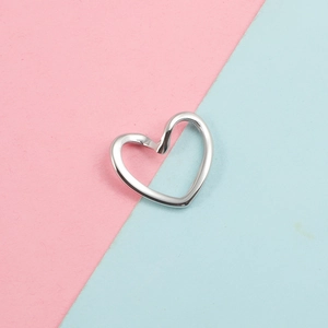 Vue détaillée d'un pendentif en forme de cœur en argent poli sur fond de couleur pastel