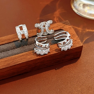 Detailansicht der silbernen Zirkon-Ohrringe mit mehrlagigem Design auf Holzsockel