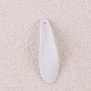 Macro detail of white pleated acrylic petal earring component on beige textured stone