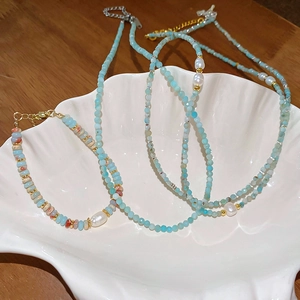 Detailed macro of gold plated geometric pearl necklace and bracelet set in a shell tray