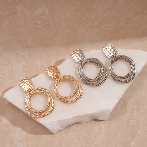Boucles d'oreilles géométriques texturées dorées et argentées sur socle en pierre