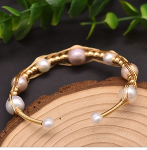 Detail of handmade gold wire-wrapped bracelet with natural irregular freshwater pearls