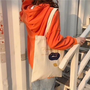 Outdoor shot of a canvas tote bag with blue abstract prints worn over the shoulder