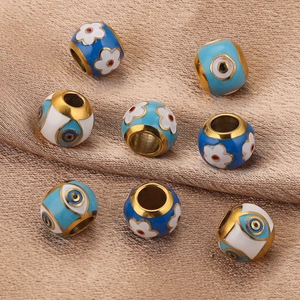 Blue and white enamel stainless steel beads scattered on gold silk fabric for DIY jewelry
