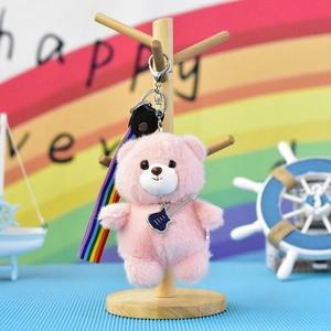Close-up of cute pink plush bear keychain with guitar charm and colorful rainbow strap accessory
