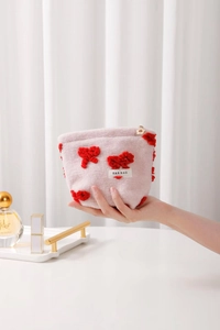 Detail of pink plush cosmetic bag with red velvet bows and star zipper pull