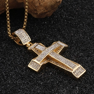 Close-up of a golden cross pendant encrusted with sparkling rhinestones on a black texture