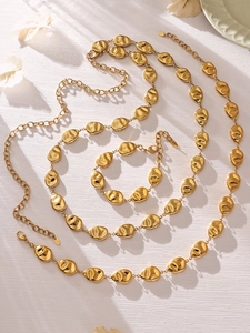 Detail view of golden irregular pleated coin charms on necklace and bracelet set