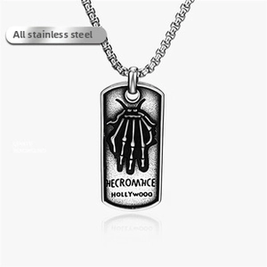 Macro detail of stainless steel rectangular pendant featuring a skull hand relief design