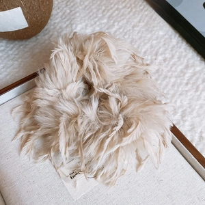 Gros plan sur la texture plumeuse du chouchou en peluche de couleur thé au lait
