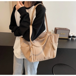 Dettaglio borsa shopper in velluto a coste beige con tasca laterale e ciondolo tessuto