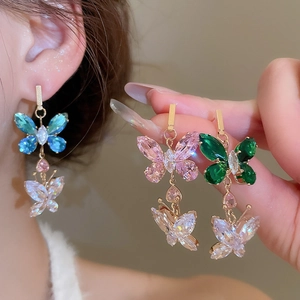 Close-up of elegant zircon butterfly drop earrings in blue, pink and green variants