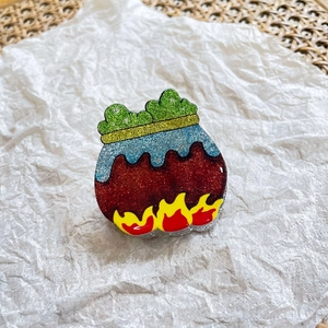 Glittery witch cauldron hair claw with green potion and fire details on white background