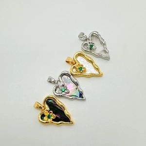 Macro detail of heart-shaped shell pendants with gold frames and green zircon flowers