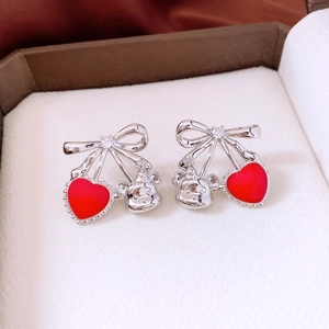 Détail de boucles d'oreilles nœud argenté avec cœur rouge et pendentifs ours 3D