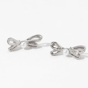 Macro shot of silver bow stud earrings with a central pearl inlay on white background