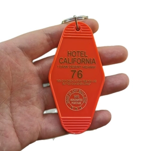 Vintage orange Hotel California Room 76 motel keychain held by hand in a close-up