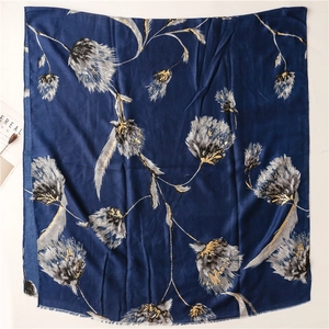 Close-up of dark blue scarf with gold foil floral pattern and delicate fringed edges