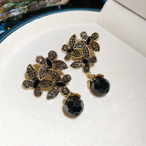 Macro detail of vintage floral earrings with black crystals and a round faceted bead pendant