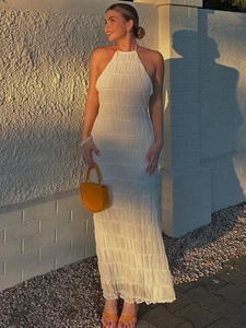 Elegant white backless pleated halter maxi dress for women in soft sunset outdoor lighting
