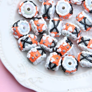 Detail of colorful hand-painted glass beads with textures on a white ceramic plate