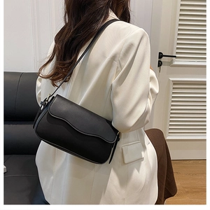 Minimalist black leather shoulder bag styled with a white blazer for business casual look