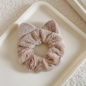 Detailed close-up of light brown plush cat ear scrunchie on a white textured tray