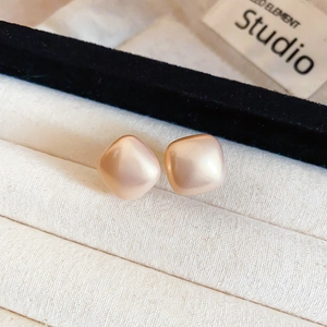 Detailed close-up of square champagne pearl earrings displayed in a luxury jewelry box