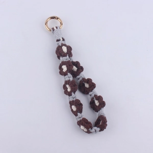 Close-up of handmade woven daisy keychain with brown cotton flower and gold metal clip