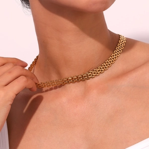 Detail of a gold-plated stainless steel watchband style necklace on a model