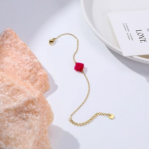 Detail of gold-plated stainless steel bracelet with magenta gemstone and S.Steel tag